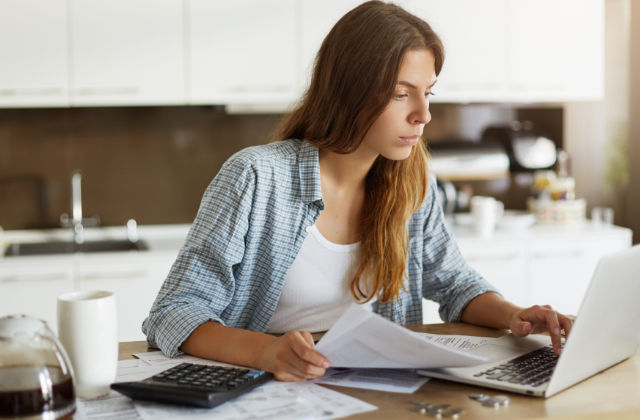 Mujer sentada a la mesa mirando en el ordenador deducciones del irpf por tu instalación fotovoltaica